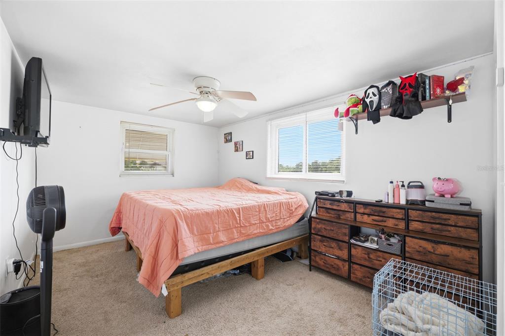 A bedroom features a bed with a peach comforter, a wooden dresser, and a ceiling fan — 13 E LEMON STREET, BEVERLY HILLS, FL