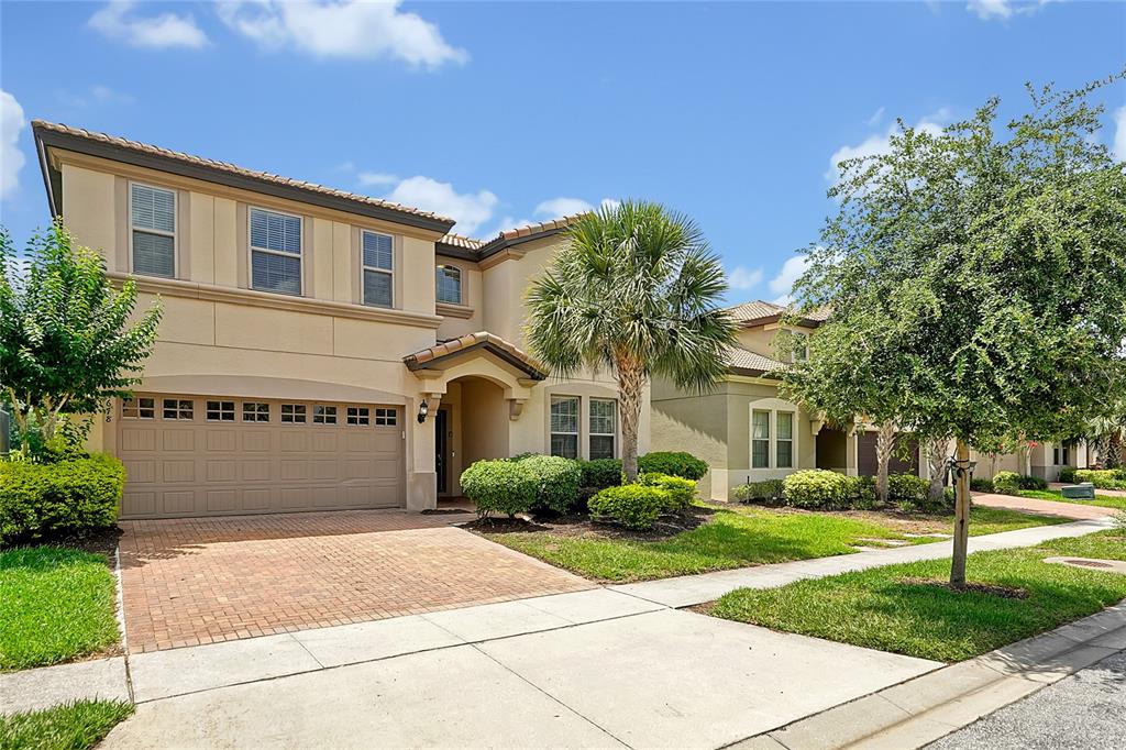 A two-story suburban house with a tan stucco exterior, a brick driveway, and a palm tree — 1678 LIMA AVE, KISSIMMEE, FL