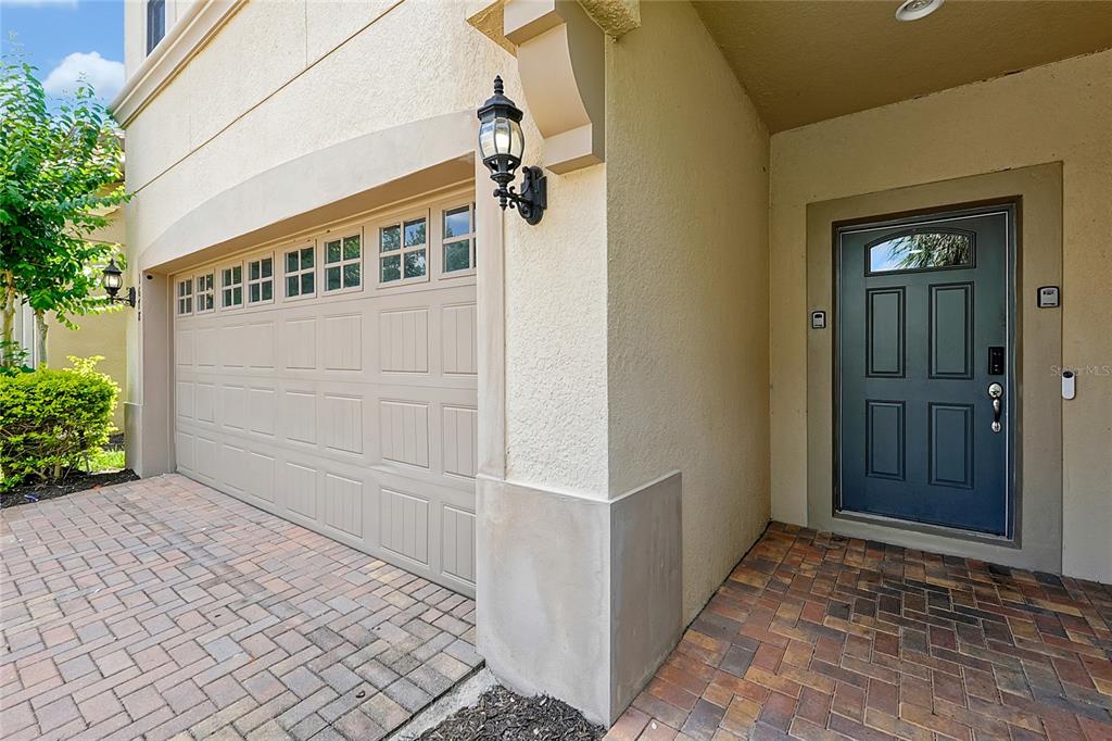 A beige stucco home exterior features a tan garage door and a dark blue front door — 1678 LIMA AVE, KISSIMMEE, FL