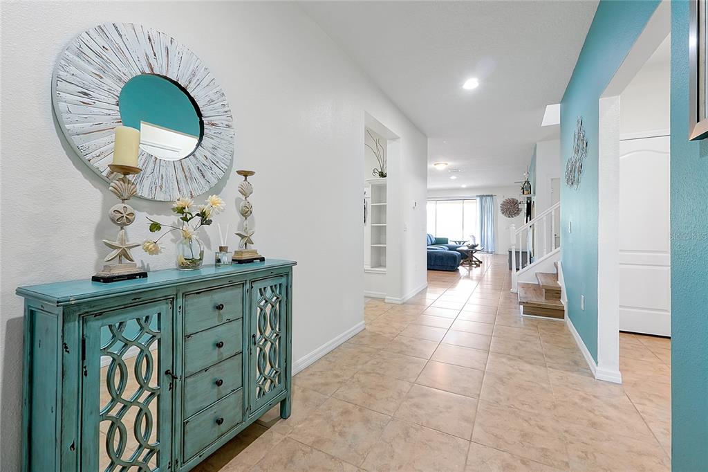 A turquoise console table sits in a tiled entryway leading to a living area — 1678 LIMA AVE, KISSIMMEE, FL