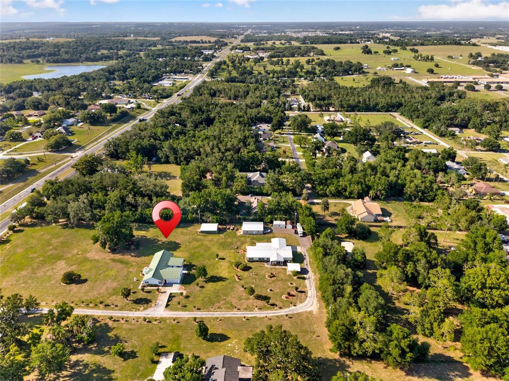 An aerial view shows a house with a green roof and outbuildings on a large lot — 9712 US HIGHWAY 301, DADE CITY, FL