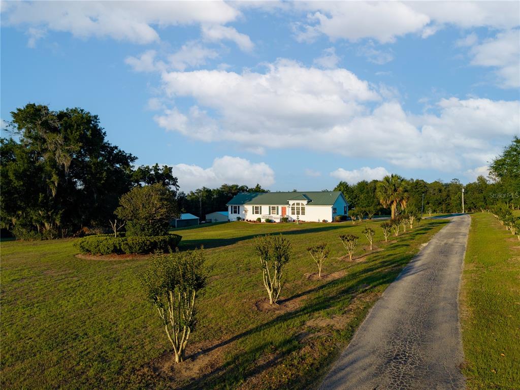 A white house with a green metal roof sits at the end of a driveway — 9712 US HIGHWAY 301, DADE CITY, FL