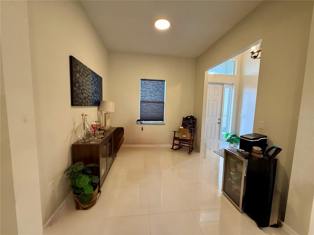 A tiled entryway features a long console table, a rocking chair, and a small refrigerator — 3312 16TH STREET W, LEHIGH ACRES, FL