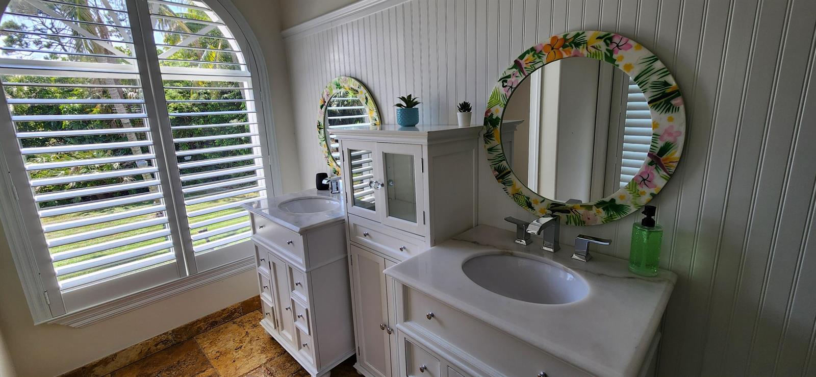 A bathroom features two white vanities with marble countertops, floral mirrors, and white beadboard walls — 1066 SE Saint Lucie Boulevard, Stuart FL 34996, STUART, FL