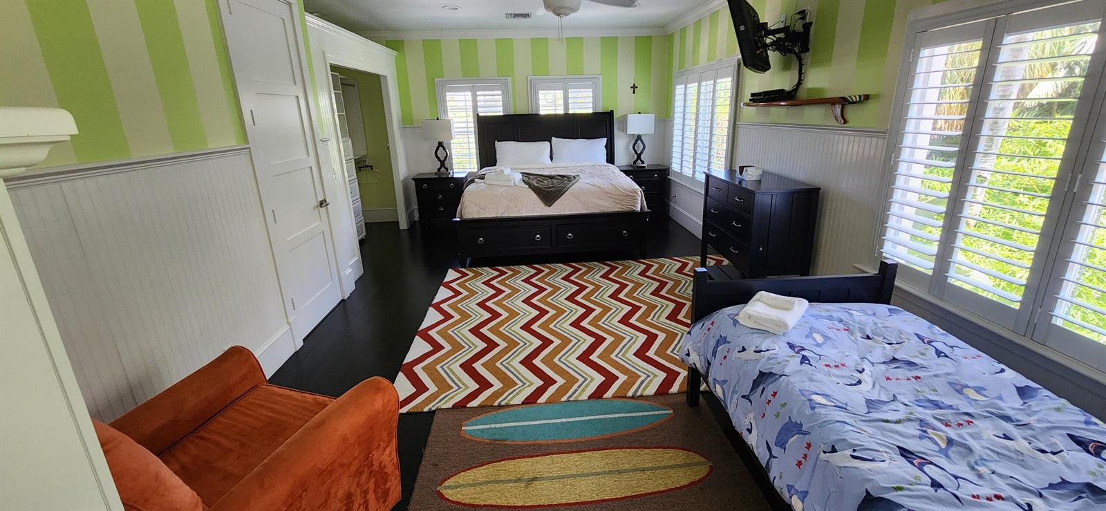 A bedroom features green striped wallpaper, a king bed, a twin bed, and two rugs — 1066 SE Saint Lucie Boulevard, Stuart FL 34996, STUART, FL