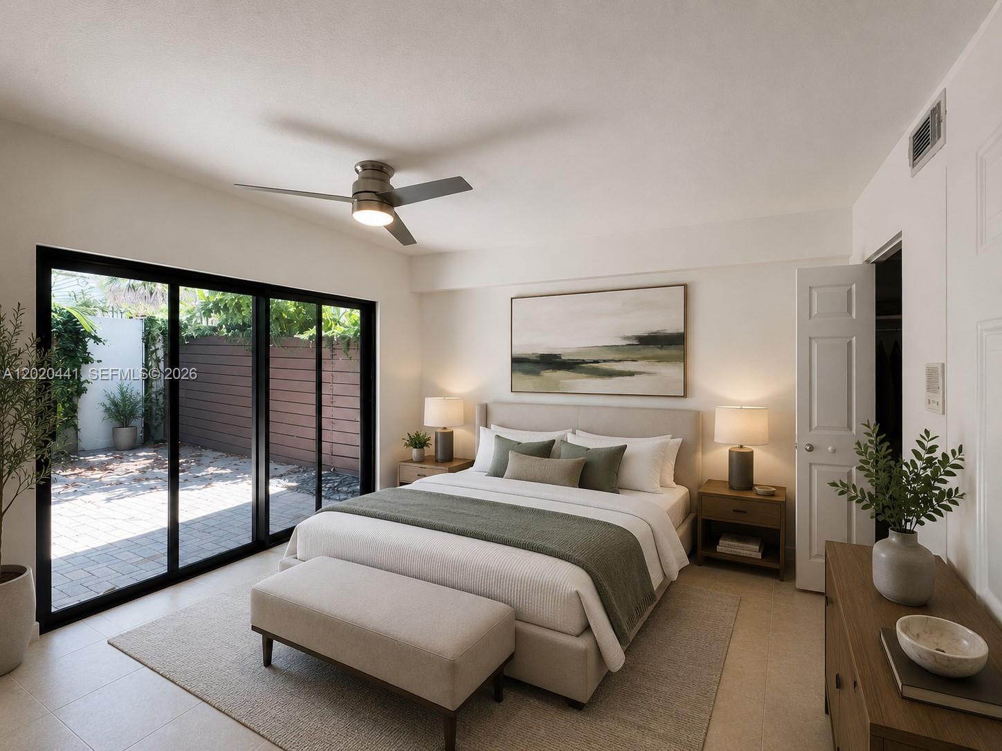 A bedroom features a bed, nightstands, a bench, and sliding glass doors opening to a patio — 3204 Bird Ave # 104, Miami FL 33133, MIAMI, FL