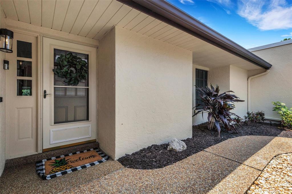 A black metal gate opens to a walkway leading toward a house entrance — 4418 LA JOLLA DRIVE, BRADENTON, FL