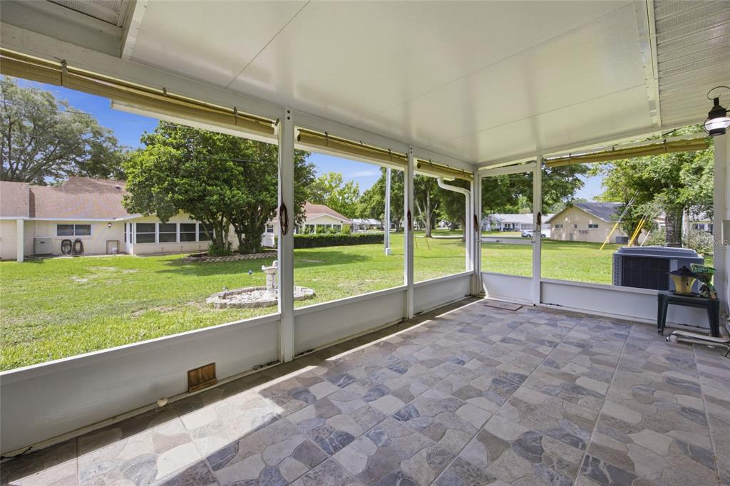 A screened-in patio features tiled flooring, a white ceiling, and views of a grassy yard — 8350 SW 93RD LANE UNIT D, OCALA, FL