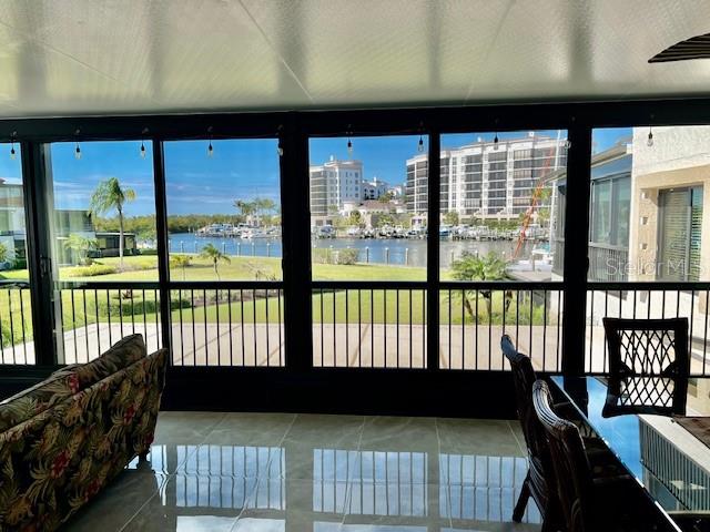 A sunroom with tile floors, a floral sofa, and large windows overlooking a waterfront marina — 3250 SOUTHSHORE DRIVE UNIT 54-B, PUNTA GORDA, FL