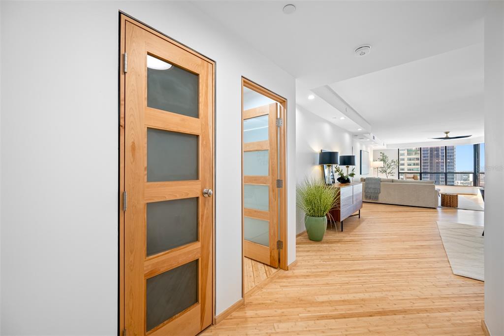 A hallway with light wood flooring leads to an open living area with floor-to-ceiling windows — 1 BEACH DRIVE SE UNIT 2211, ST PETERSBURG, FL