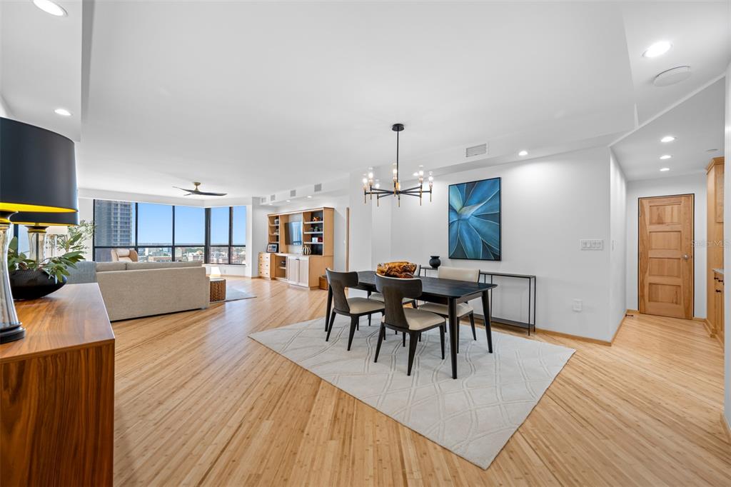 A dining area with a modern chandelier and wood flooring opens into a living room — 1 BEACH DRIVE SE UNIT 2211, ST PETERSBURG, FL
