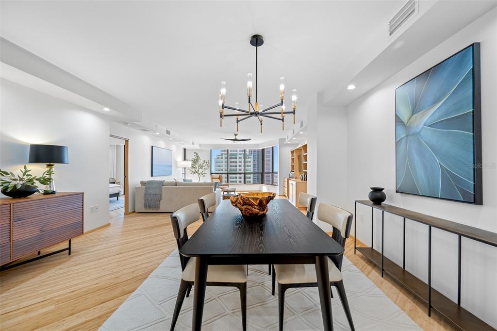 A dining room with a black table, modern chandelier, and large blue floral wall art — 1 BEACH DRIVE SE UNIT 2211, ST PETERSBURG, FL