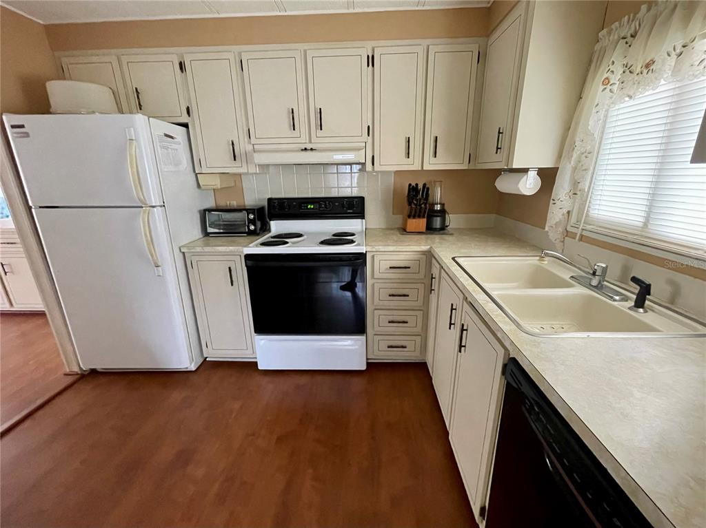 A kitchen features off-white cabinets, a white refrigerator, a black stove, and laminate countertops — 140 MOUNTAIN FIR DRIVE, PALM HARBOR, FL