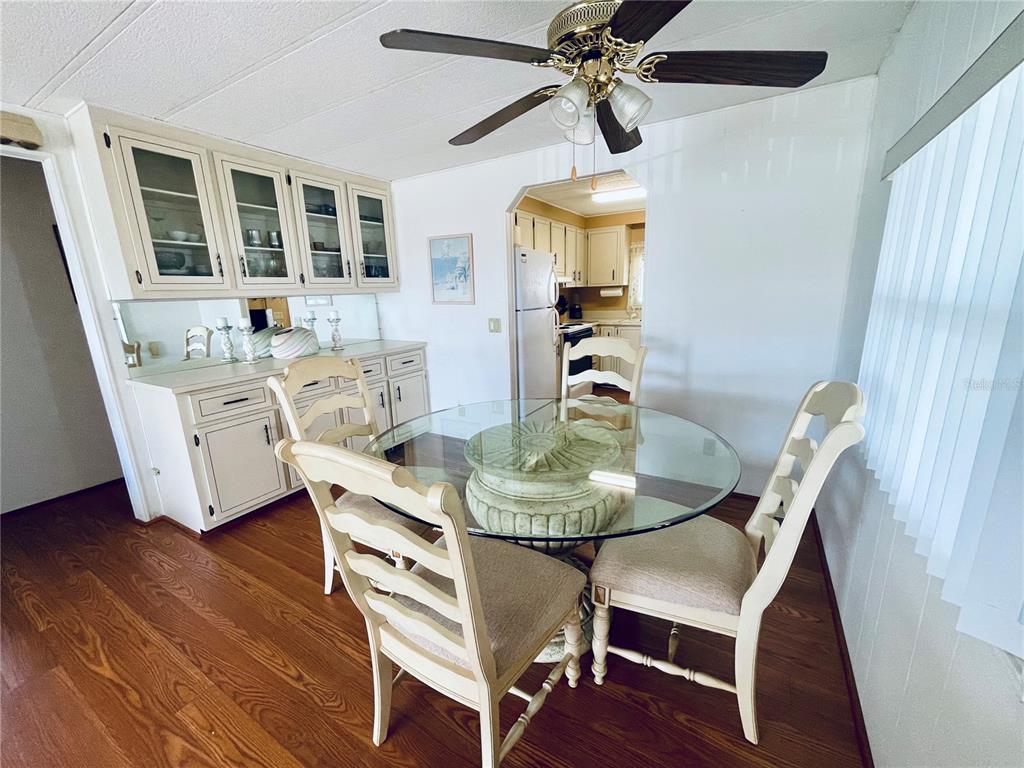 A dining room features a glass-topped table, matching chairs, and built-in cabinetry with glass doors — 140 MOUNTAIN FIR DRIVE, PALM HARBOR, FL