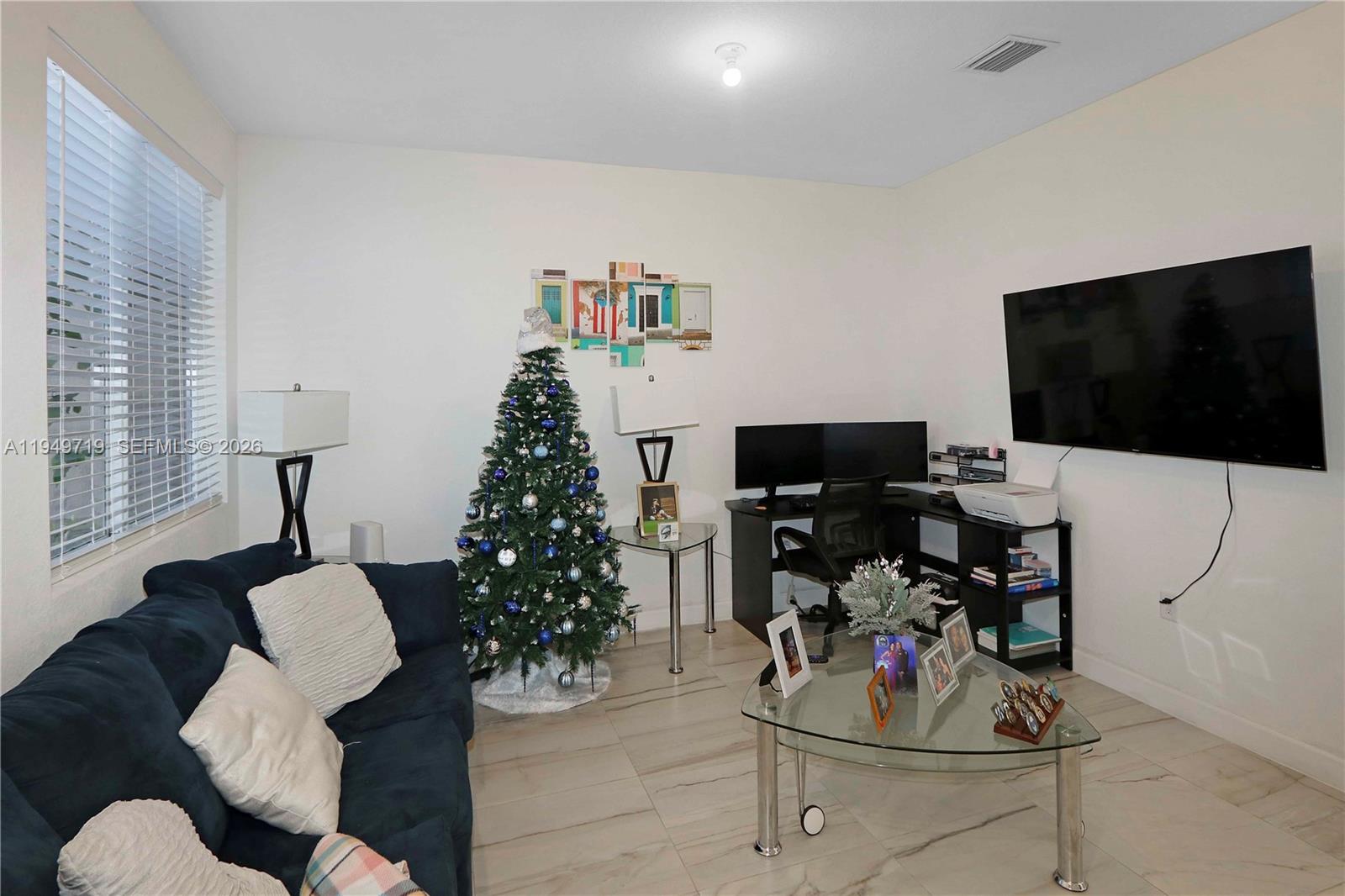 A living room features a dark blue sofa, a Christmas tree, and a corner desk — 2432 SE 10th Ct, Homestead FL 33035, HOMESTEAD, FL