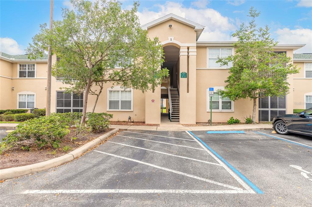 A two-story apartment building exterior with a central staircase and a paved parking lot — 830 AIRPORT ROAD UNIT 105, PORT ORANGE, FL