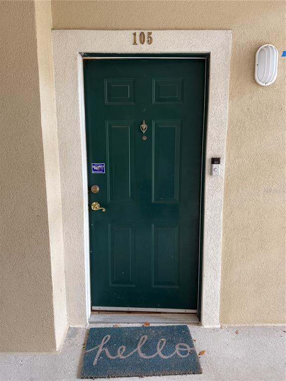 A dark green front door with a brass handle and a hello doormat — 830 AIRPORT ROAD UNIT 105, PORT ORANGE, FL