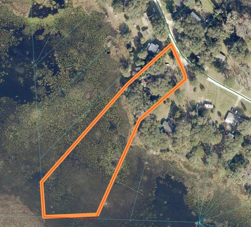 An aerial view shows a residential lot outlined in orange, bordering a large wetland area — 14120 NE 110TH AVENUE ROAD, FORT MC COY, FL