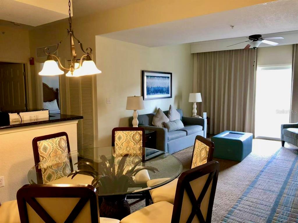 A dining area with a glass table and chairs sits in front of a living room — 8125 RESORT VILLAGE DRIVE UNIT 5808, ORLANDO, FL