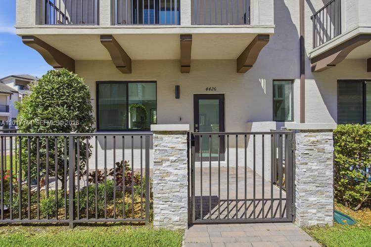 A gated stone-paved patio leads to the front entrance of a multi-story townhouse — 4426 83rd Pkwy, Doral FL 33166, DORAL, FL