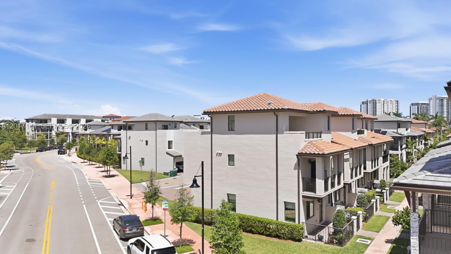 An exterior view of multi-story townhouses with tiled roofs along a curved street — 4426 83rd Pkwy, Doral FL 33166, DORAL, FL