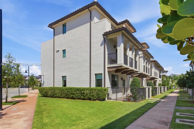 A multi-story townhouse with a beige stucco exterior, balconies, and a manicured lawn — 4426 83rd Pkwy, Doral FL 33166, DORAL, FL