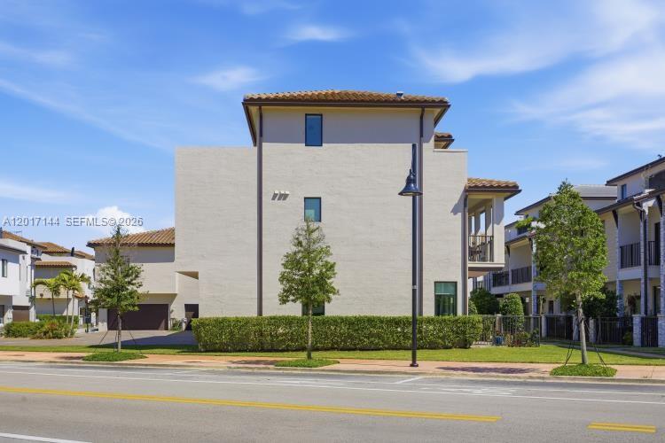 The exterior of a multi-story stucco townhouse features a tiled roof and a manicured hedge — 4426 83rd Pkwy, Doral FL 33166, DORAL, FL