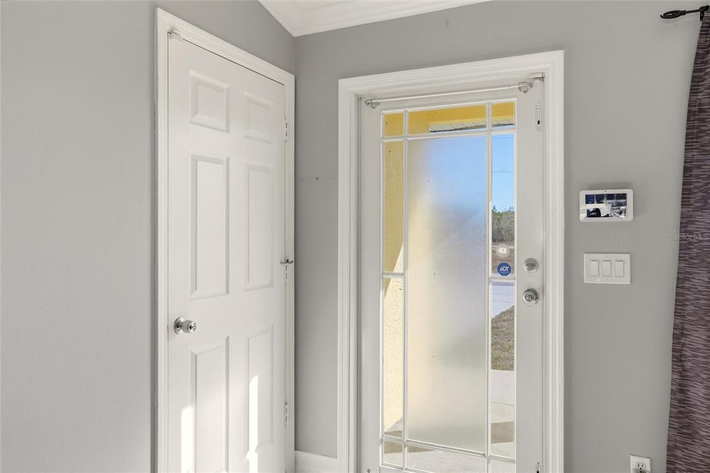 A white interior door sits next to a glass-paneled front door with a security system — 1209 NW 19TH STREET, CAPE CORAL, FL