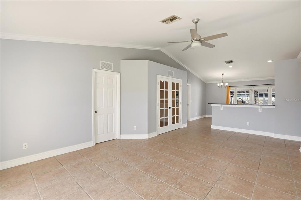 A living room with light gray walls, tile flooring, a ceiling fan, and French doors — 1209 NW 19TH STREET, CAPE CORAL, FL