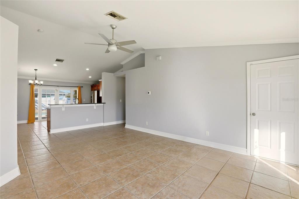 An open-concept living area features light gray walls, tile flooring, and a kitchen breakfast bar — 1209 NW 19TH STREET, CAPE CORAL, FL