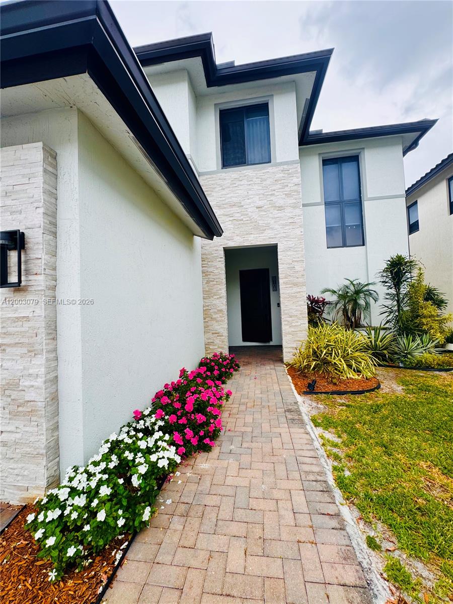 A paved walkway leads to the front entrance of a two-story house with stone accents — 8108 NW 48th Ter # 8108, Doral FL 33166, DORAL, FL