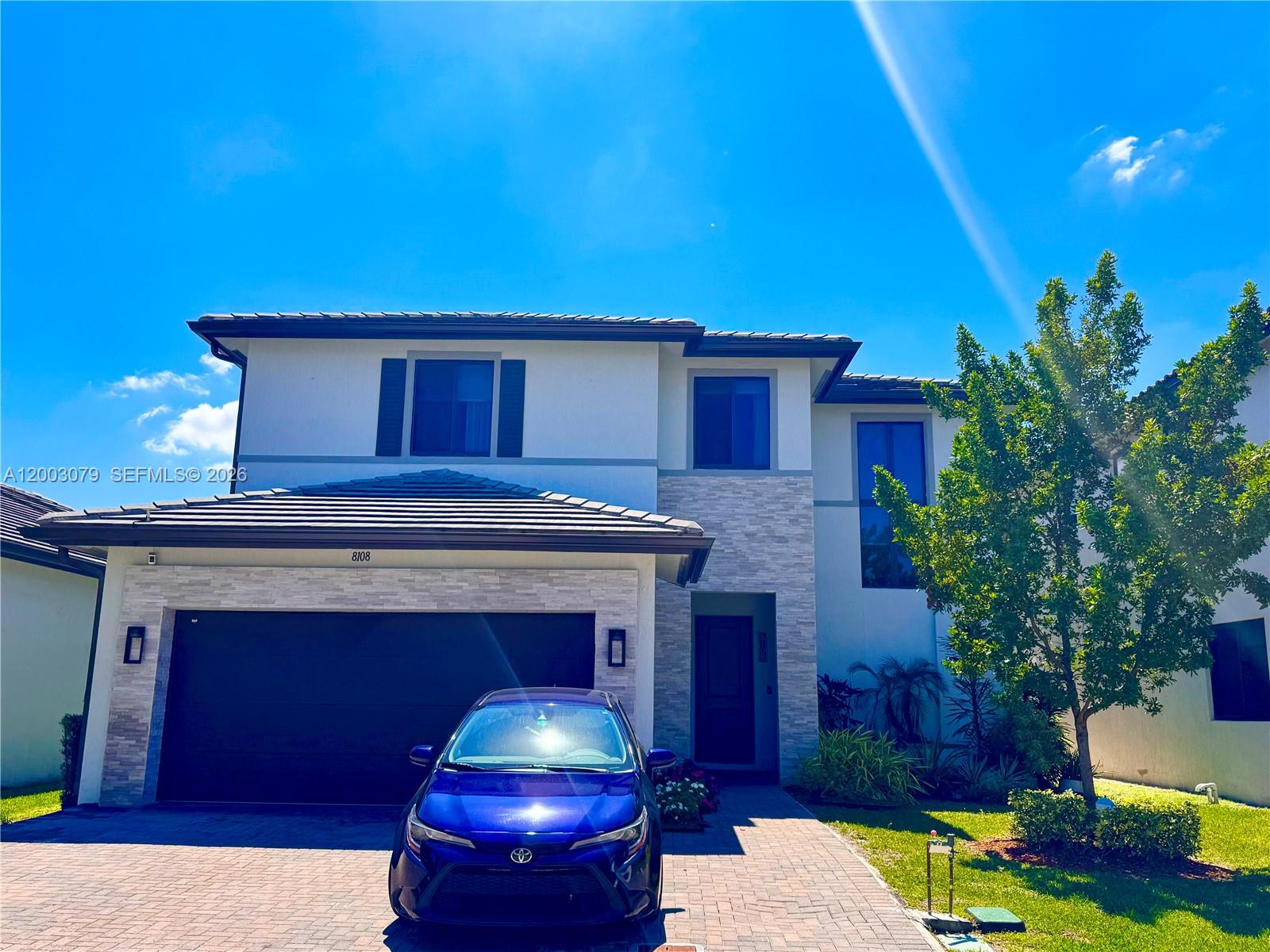 A two-story house with a stone-accented facade, a two-car garage, and a blue car parked outside — 8108 NW 48th Ter # 8108, Doral FL 33166, DORAL, FL