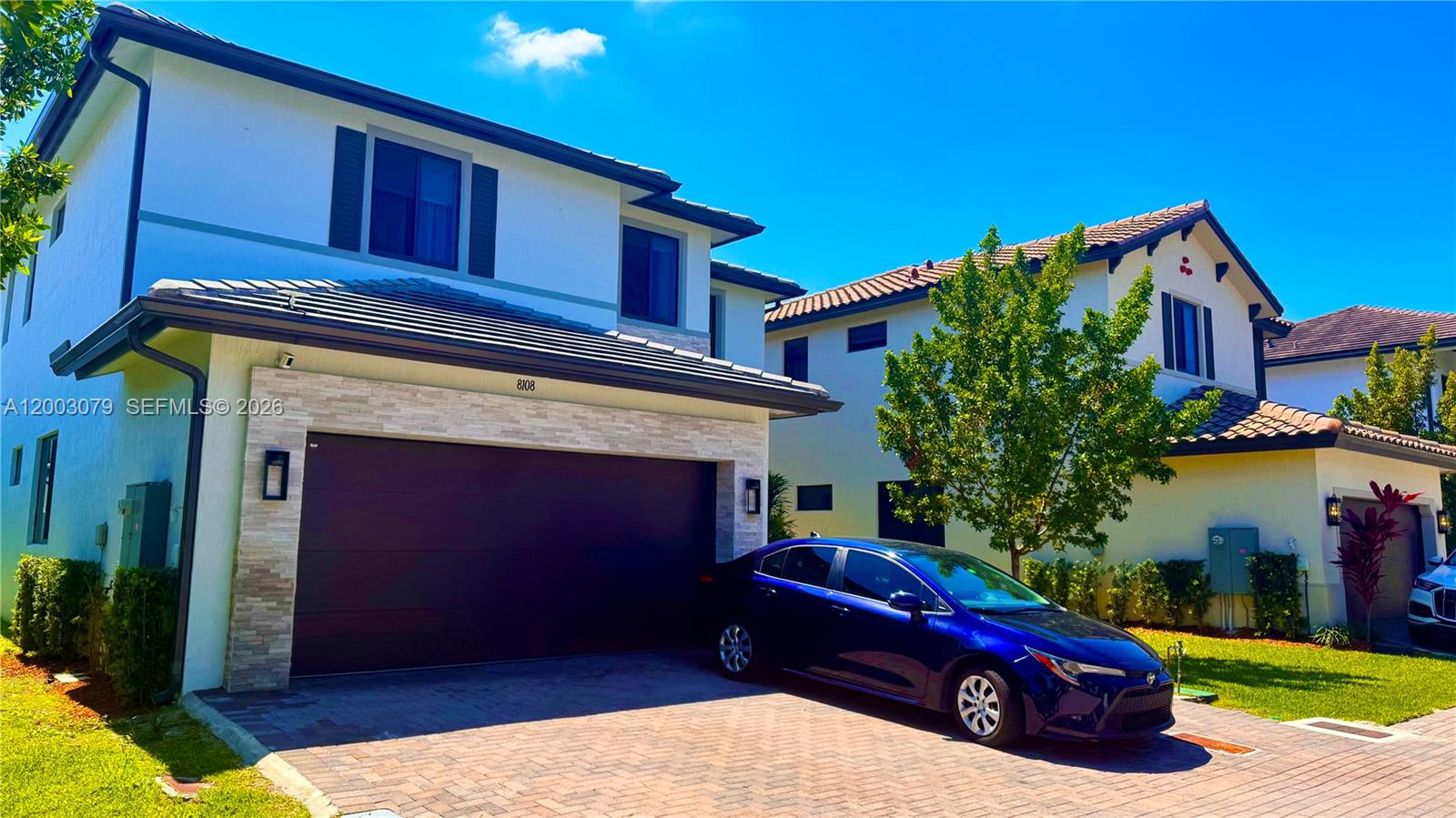A two-story house with a two-car garage and a blue sedan parked in the driveway — 8108 NW 48th Ter # 8108, Doral FL 33166, DORAL, FL