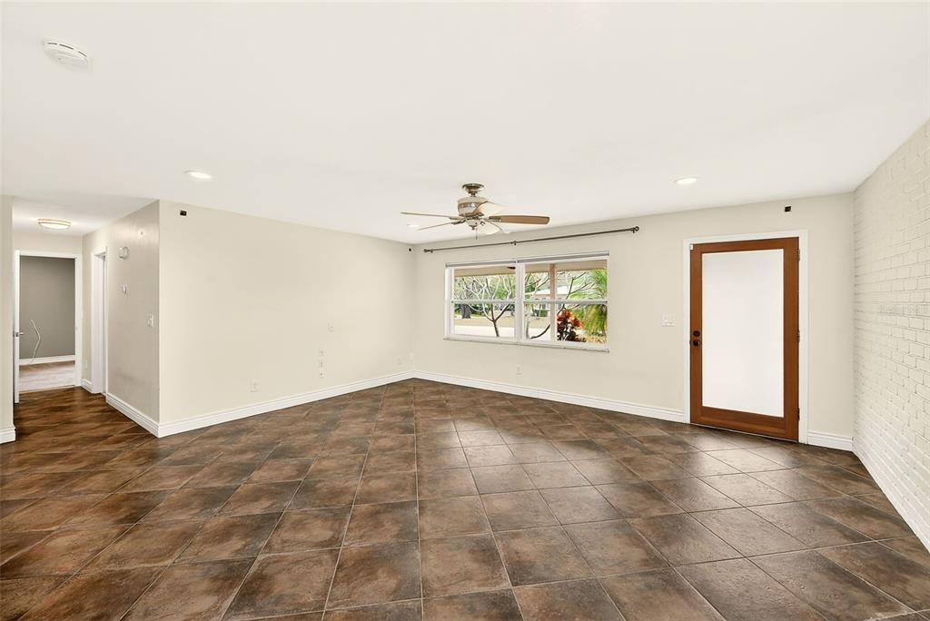 An empty room with dark tile flooring, a ceiling fan, and a glass-paneled exterior door — 1465 BAYVIEW DRIVE, CLEARWATER, FL