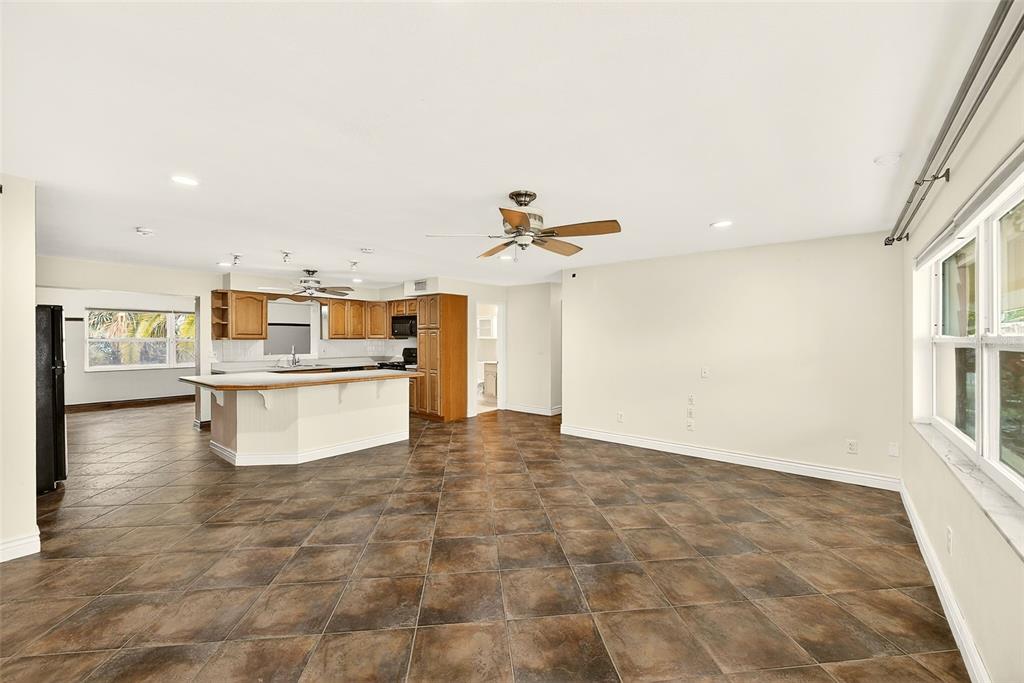 An open-concept kitchen and living area with brown tile flooring and a ceiling fan — 1465 BAYVIEW DRIVE, CLEARWATER, FL
