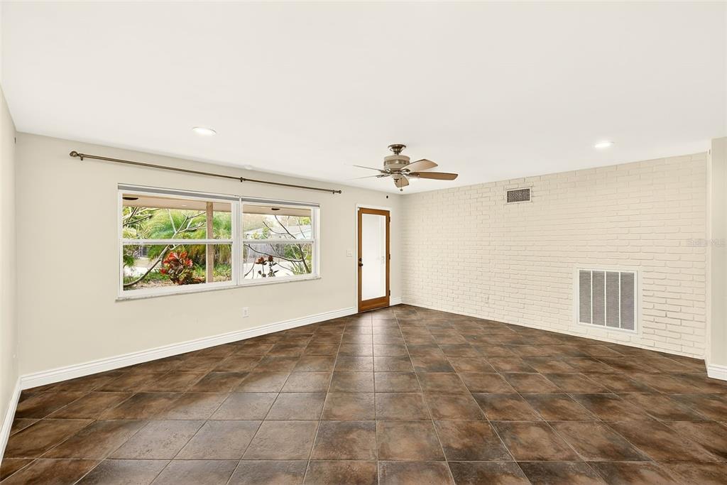 A room with dark tile flooring, a white brick wall, and a ceiling fan — 1465 BAYVIEW DRIVE, CLEARWATER, FL