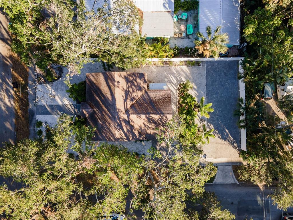 An aerial view shows a house with a brown roof surrounded by trees and landscaping — 1704 WISCONSIN LANE, SARASOTA, FL