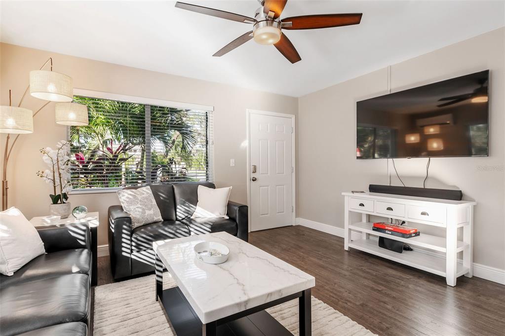 A living room features dark leather sofas, a white coffee table, and a wall-mounted television — 1704 WISCONSIN LANE, SARASOTA, FL