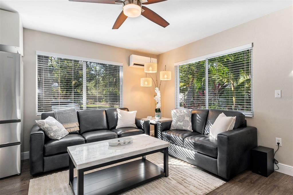 A living room features two black leather sofas, a marble coffee table, and large windows — 1704 WISCONSIN LANE, SARASOTA, FL