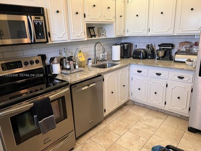 A kitchen features white cabinetry, stainless steel appliances, and light-colored granite countertops — 2901 S Palm Aire Dr # 603, Pompano Beach FL 33069, POMPANO BEACH, FL
