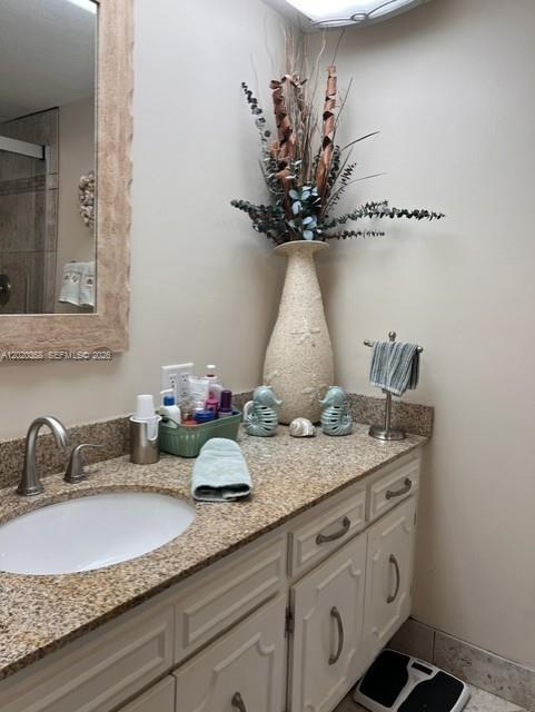 A bathroom vanity features a granite countertop, white cabinets, and a tall decorative vase — 2901 S Palm Aire Dr # 603, Pompano Beach FL 33069, POMPANO BEACH, FL