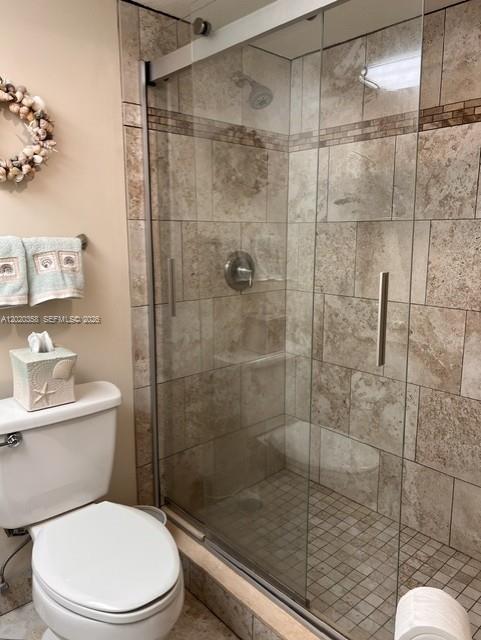 A bathroom features a toilet, a seashell wreath, and a glass-enclosed shower with tiled walls — 2901 S Palm Aire Dr # 603, Pompano Beach FL 33069, POMPANO BEACH, FL