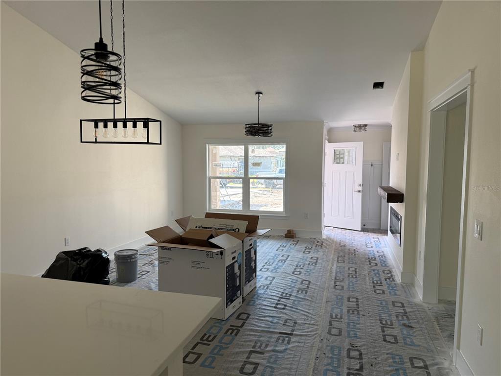 An unfinished dining area features two modern light fixtures, a large window, and protective floor paper — 64 EMERSON DRIVE, PALM COAST, FL
