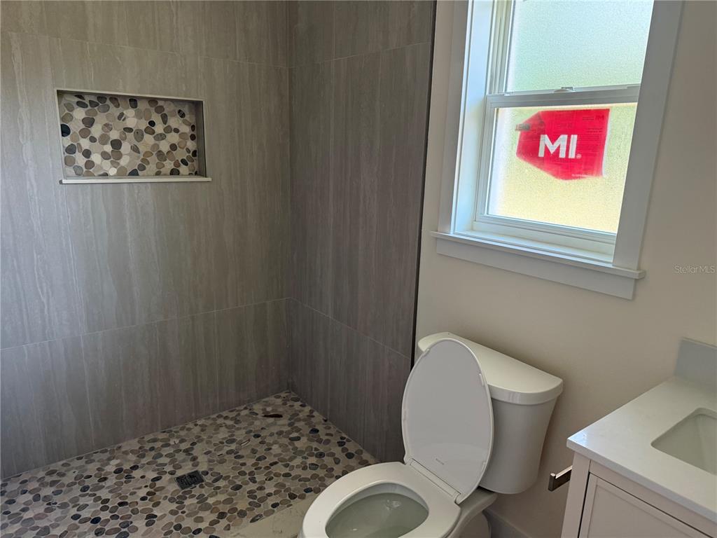 A bathroom features a walk-in shower with pebble flooring and a tiled niche — 64 EMERSON DRIVE, PALM COAST, FL