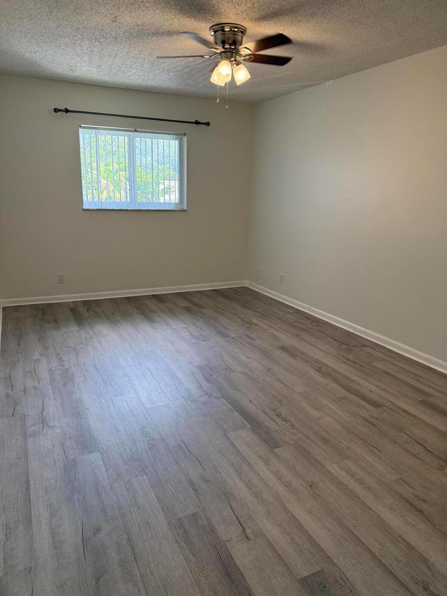 An empty bedroom features light gray wood-look flooring, white walls, and a ceiling fan — 255 S Cypress Road # 339, Pompano Beach FL 33060, POMPANO BEACH, FL