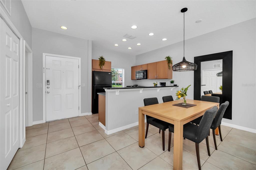 A dining area with a wooden table and chairs sits adjacent to a kitchen counter — 3070 YELLOW LANTANA LANE, KISSIMMEE, FL