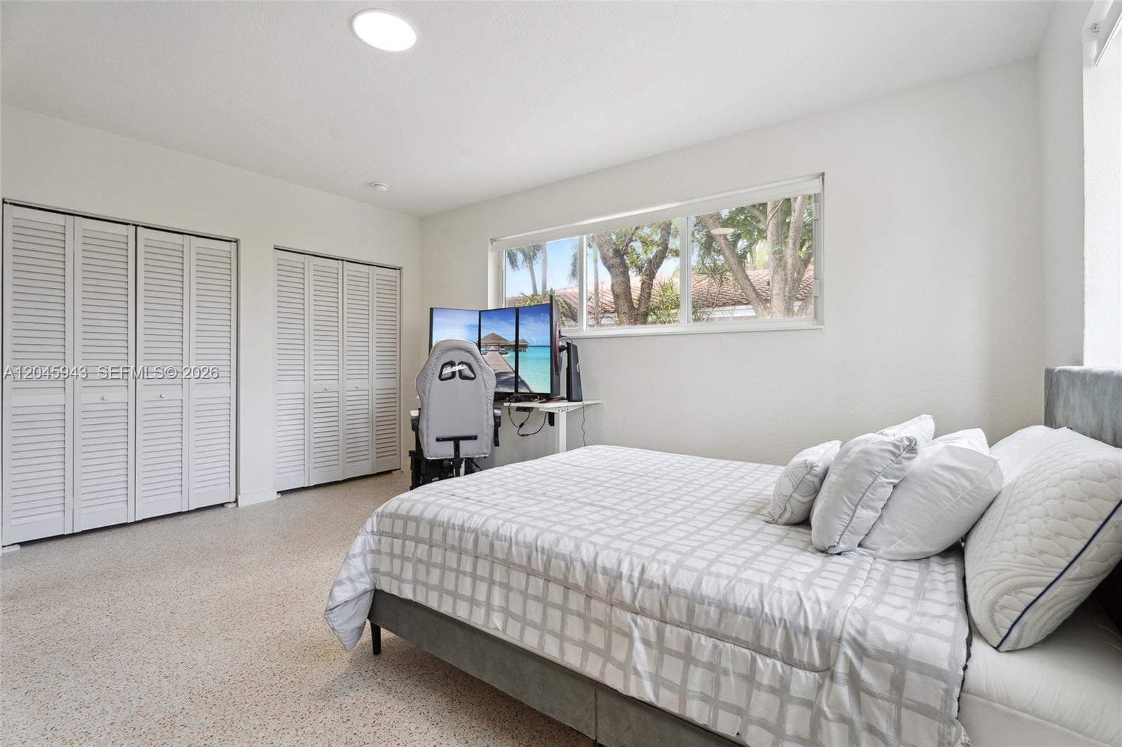 A bedroom features a bed, a desk with triple monitors, and white louvered closet doors — 835 80th St # 3, Miami Beach FL 33141, MIAMI BEACH, FL