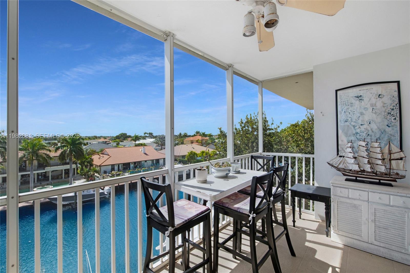 A screened balcony features a dining set, a model ship, and views of a canal — 3050 NE 48th Ct # 401, Lighthouse Point FL 33064, LIGHTHOUSE POINT, FL