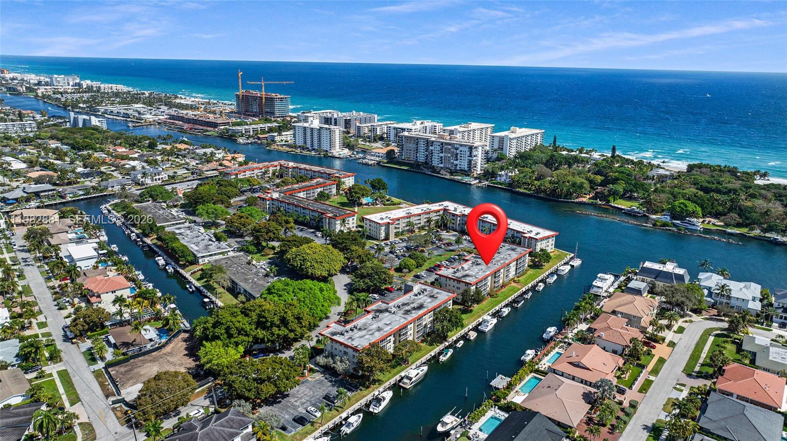 An aerial view shows a multi-story apartment complex situated along a canal near the ocean — 3050 NE 48th Ct # 401, Lighthouse Point FL 33064, LIGHTHOUSE POINT, FL