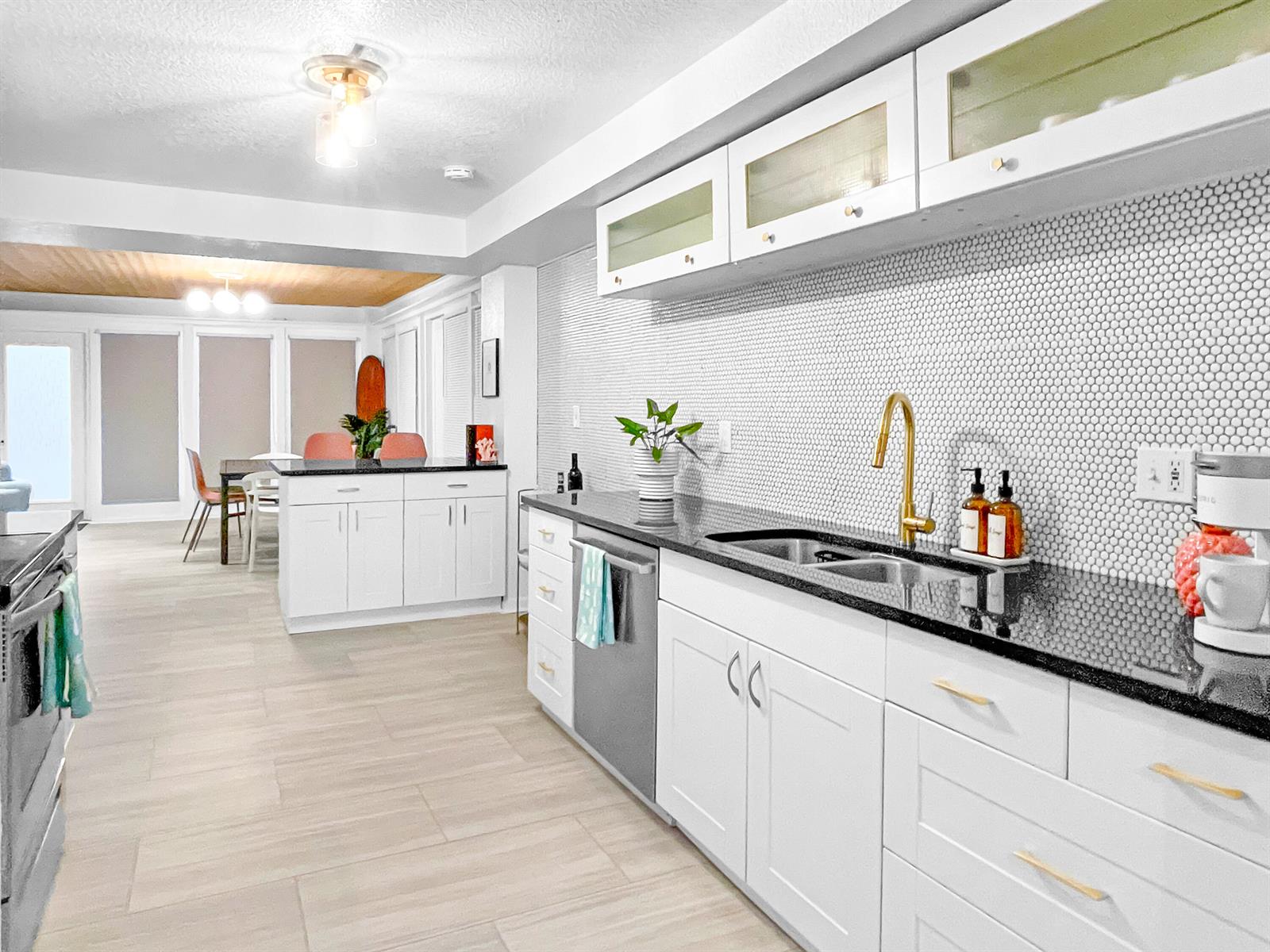 A kitchen features white cabinets, black countertops, a penny tile backsplash, and gold hardware — 1114 N M Street, FL 33460, FL